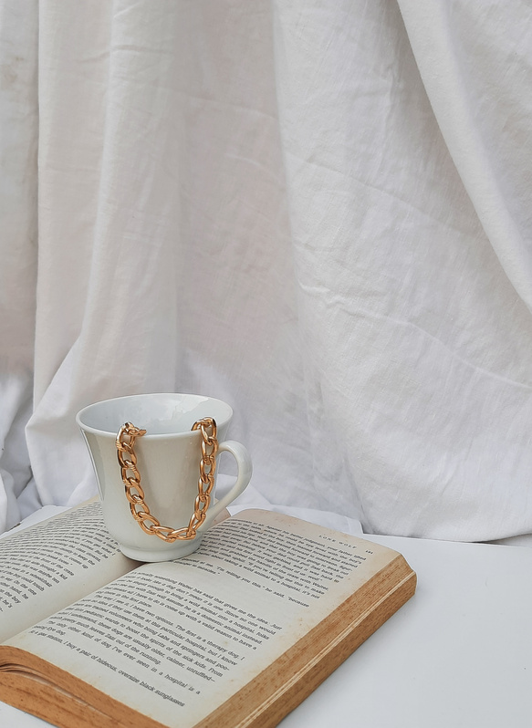 Photo of a Gold Chain Necklace in a White Ceramic Mug